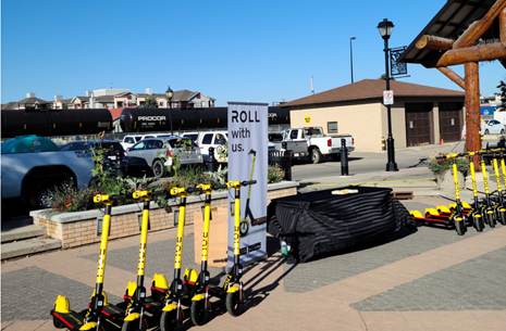 Group of E-Scooters parked on the sidewalk near signage promoting for their use